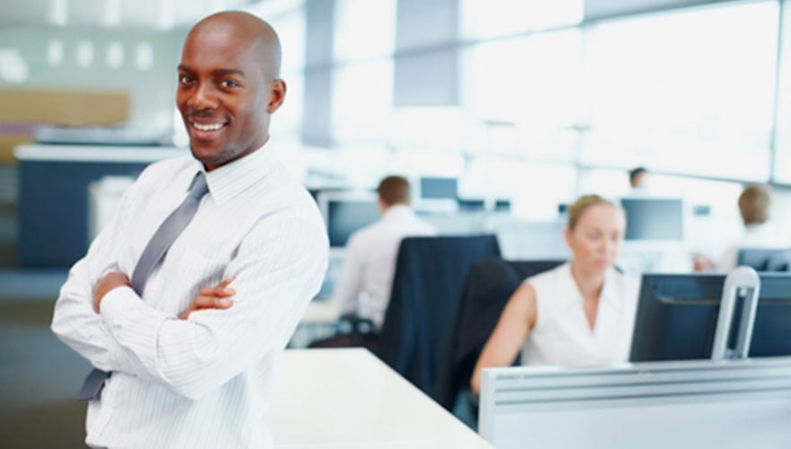Smiling man standing in front of employees working at desks