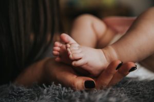 Doula with a hand on a baby's foot