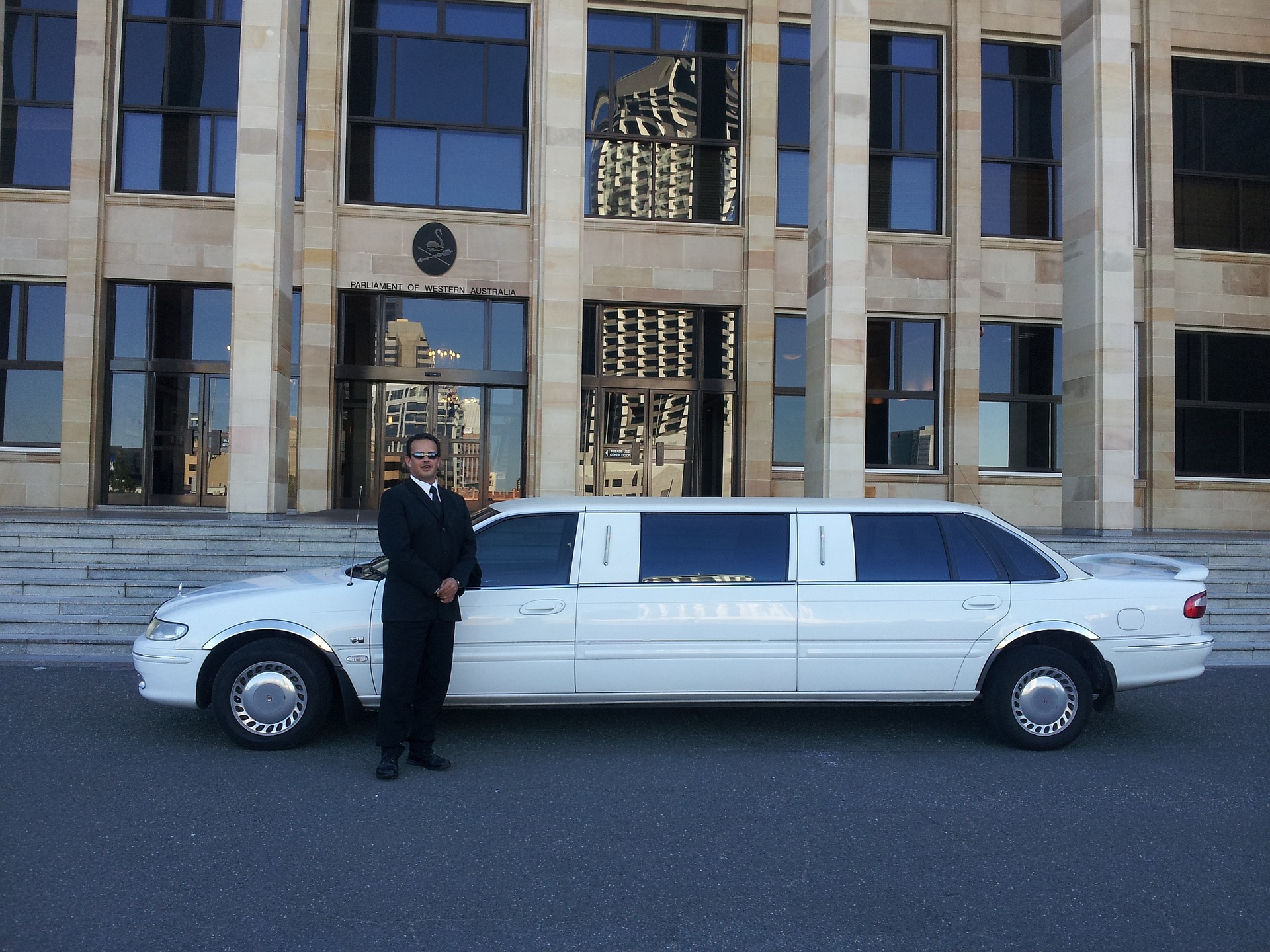 man in suit next to white limo